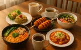 Korean breakfast spread with ramen, kimchi rice, cheese corn dogs, bibimbap, tteokbokki, and coffee served on a wooden table – authentic Korean food by Wang House Korean Café.