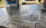 A concrete patio with a fire pit, providing a cozy outdoor space for relaxation and gatherings.
